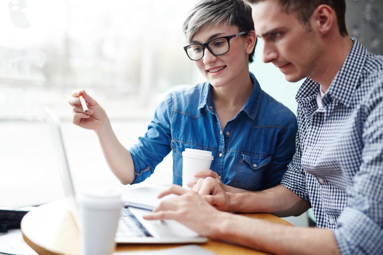 Two people collaborating over a laptop to build a website